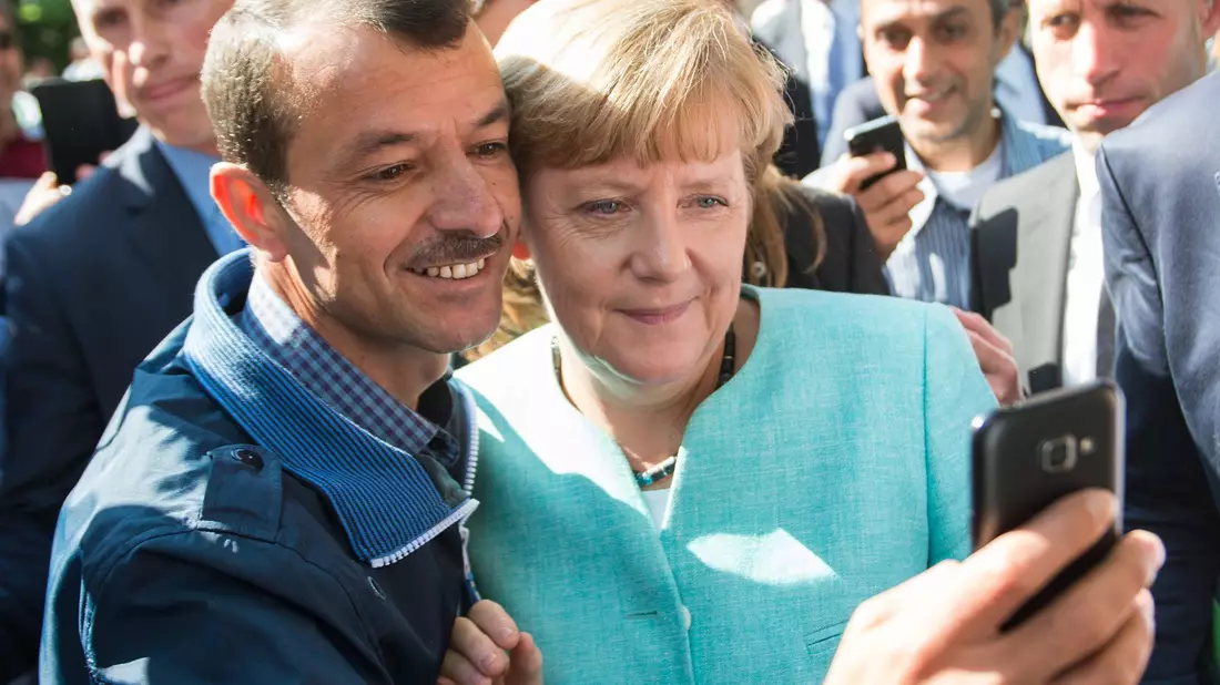 Bald zehn Jahre her: Angela Merkel (CDU) lässt sich nach dem Besuch einer Erstaufnahmeeinrichtung für Asylbewerber in Berlin-Spandau für ein Selfie zusammen mit einem Flüchtling fotografieren. (Archivbild) - Bild: Bernd von Jutrczenka/dpa