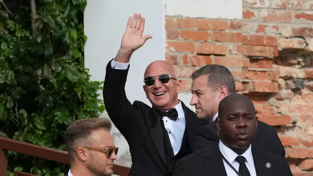Amazon-Gründer Jeff Bezos winkt Paparazzi zu. - Bild: Antonio Calanni/AP/dpa