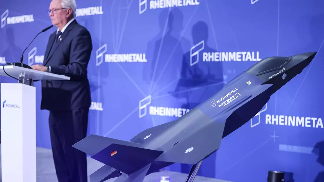 Ein Modell des F-35 auf der Bühne, auf der Konzernchef Papperger zu Mitarbeitern spricht. - Bild: Oliver Berg/dpa