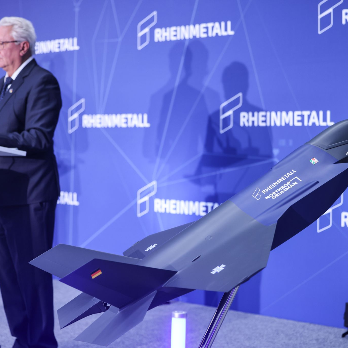 Ein Modell des F-35 auf der Bühne, auf der Konzernchef Papperger zu Mitarbeitern spricht. - Foto: Oliver Berg/dpa