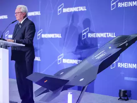 Ein Modell des F-35 auf der Bühne, auf der Konzernchef Papperger zu Mitarbeitern spricht. - Foto: Oliver Berg/dpa