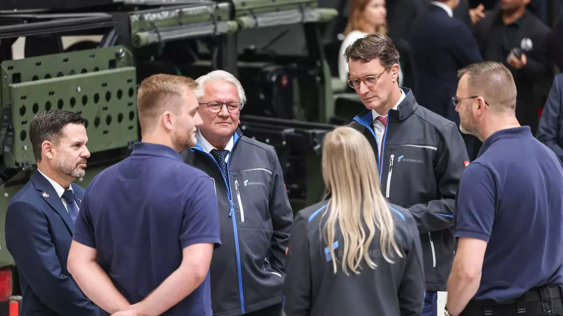 Rheinmetall-Chef Armin Papperger (Dritter von links) und NRW-Ministerpräsident Hendrik Wüst (zweiter von rechts) bei einem Rundgang durch die F-35-Produktionsanlage. - Bild: Oliver Berg/dpa