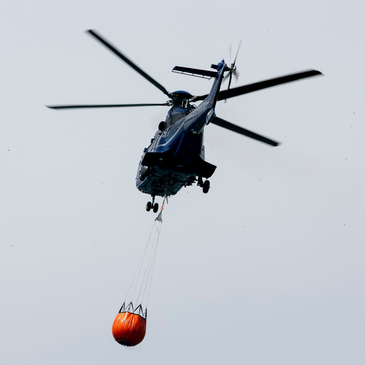 Ein Löschhubschrauber der Bundespolizei fliegt über dem Zeithainer Tagebau und nimmt Wasser auf, um den Waldbrand Gohrischheide zu bekämpfen. - Foto: Daniel Wagner/dpa