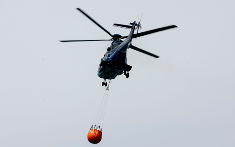 Ein Löschhubschrauber der Bundespolizei fliegt über dem Zeithainer Tagebau und nimmt Wasser auf, um den Waldbrand Gohrischheide zu bekämpfen. - Foto: Daniel Wagner/dpa