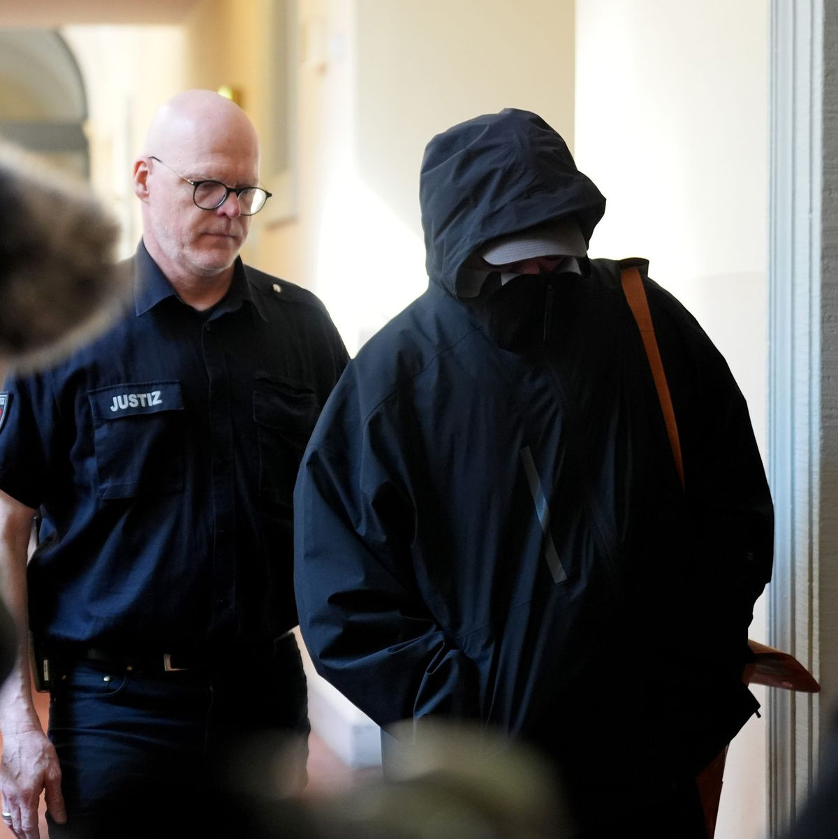 Ein Angeklagter wird von einem Polizisten zum Gerichtssaal begleitet.  - Foto: Marcus Brandt/dpa