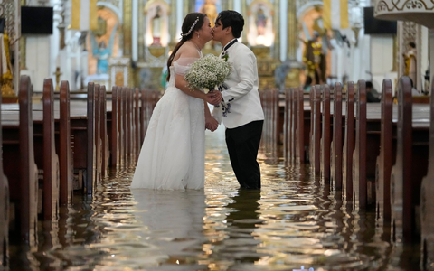 Die Braut ließ sich von den Wassermassen nicht beirren. - Foto: Aaron Favila/AP/dpa
