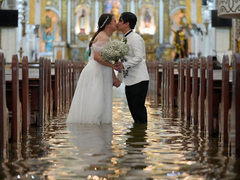 Die Braut ließ sich von den Wassermassen nicht beirren. - Foto: Aaron Favila/AP/dpa