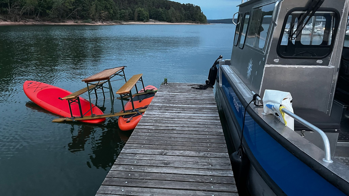 Das Trio war auf einer Konstruktion aus Surfbrettern und einer Bierbank auf dem Brombachsee unterwegs. Bild: Polizei Mittelfranken - Foto: -/Polizei Mittelfranken/dpa