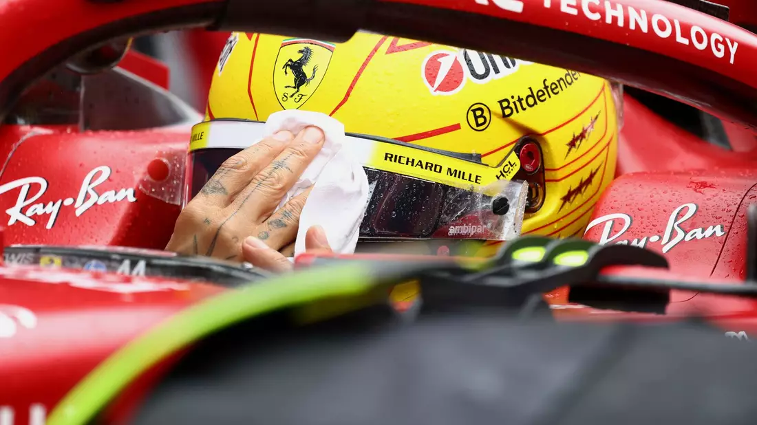 Lewis Hamilton wischt sich den Regen vom Visier. - Bild: Yves Herman/Pool Reuters/AP/dpa