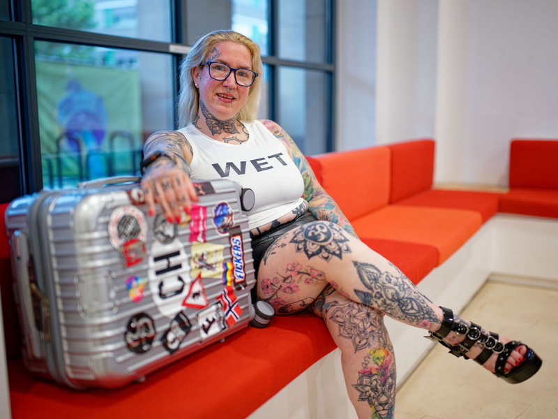 «Mimi» sitzt kurz vor der Abreise ins französische Cap d’Agde mit ihrem Koffer im Mannheimer Rathaus. - Foto: Uwe Anspach/dpa