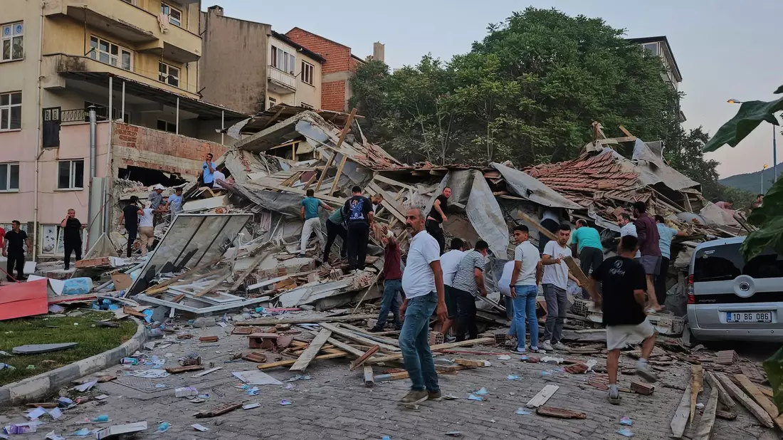 Menschen beseitigen in Sindirgi die Trümmer eines eingestürzten Gebäudes. - Bild: Bahadir Demirceviren/IHA/AP/dpa