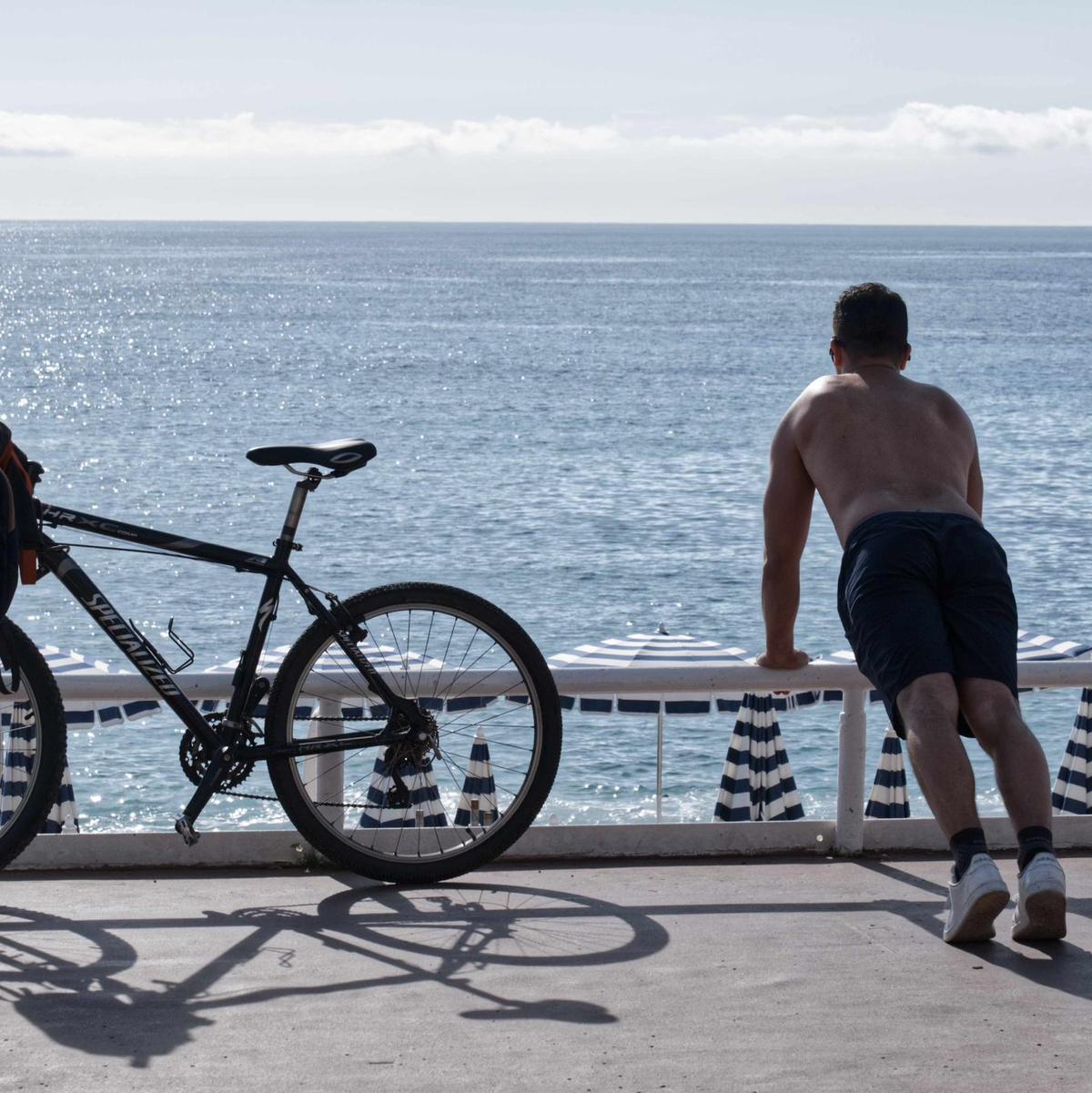 Ein Mann mit nacktem Oberkörper macht am Strand von Nizza neben seinem Fahrrad Übungen. (Archivbild) - Foto: Serge Haouzi/XinHua/dpa