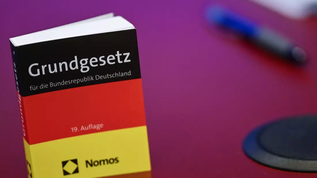 Das Grundgesetz in Miniatur-Ausgabe steht bei der Pressekonferenz zur AfD auf einem Tisch.  - Bild: Britta Pedersen/dpa