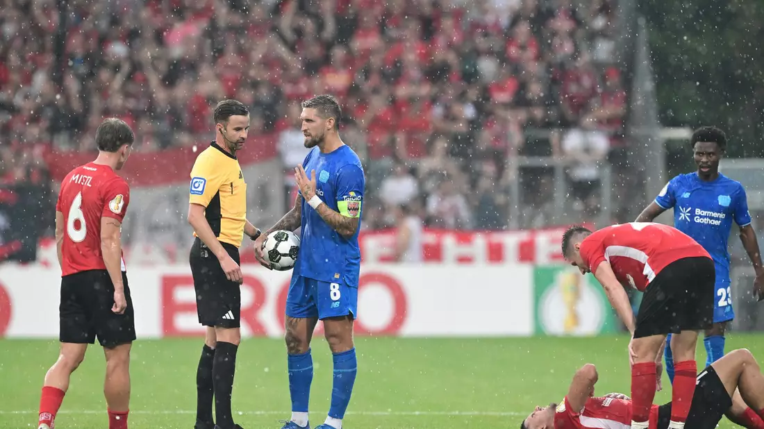 Schiedsrichter Michael Bacher (2.v.l.) muss das Spiel in Großaspach unterbrechen  - Bild: Bernd Weißbrod/dpa