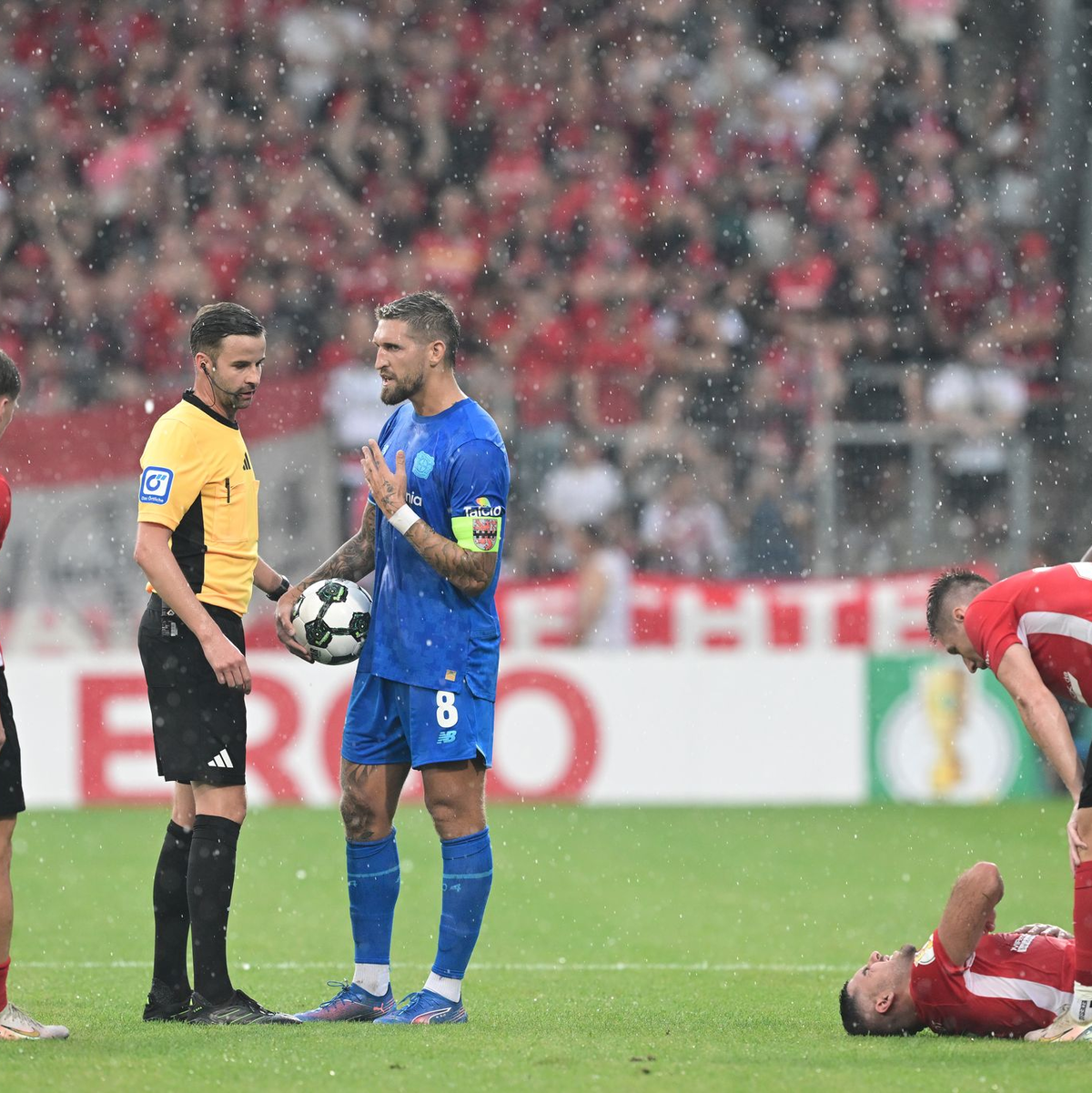 Schiedsrichter Michael Bacher (2.v.l.) muss das Spiel in Großaspach unterbrechen  - Foto: Bernd Weißbrod/dpa