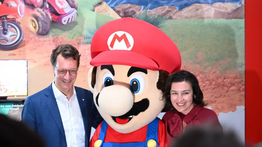 Beim Messerundgang über die Gamescom kam der Tross von Politikern auch beim Messestand von Nintendo vorbei, hier stehen NRW-Ministerpräsident Hendrik Wüst (CDU) und Bundesforschungsministerin Dorothee Bär (CSU) neben einer Mario-Plüschfigur. - Bild: Wolf von Dewitz/dpa