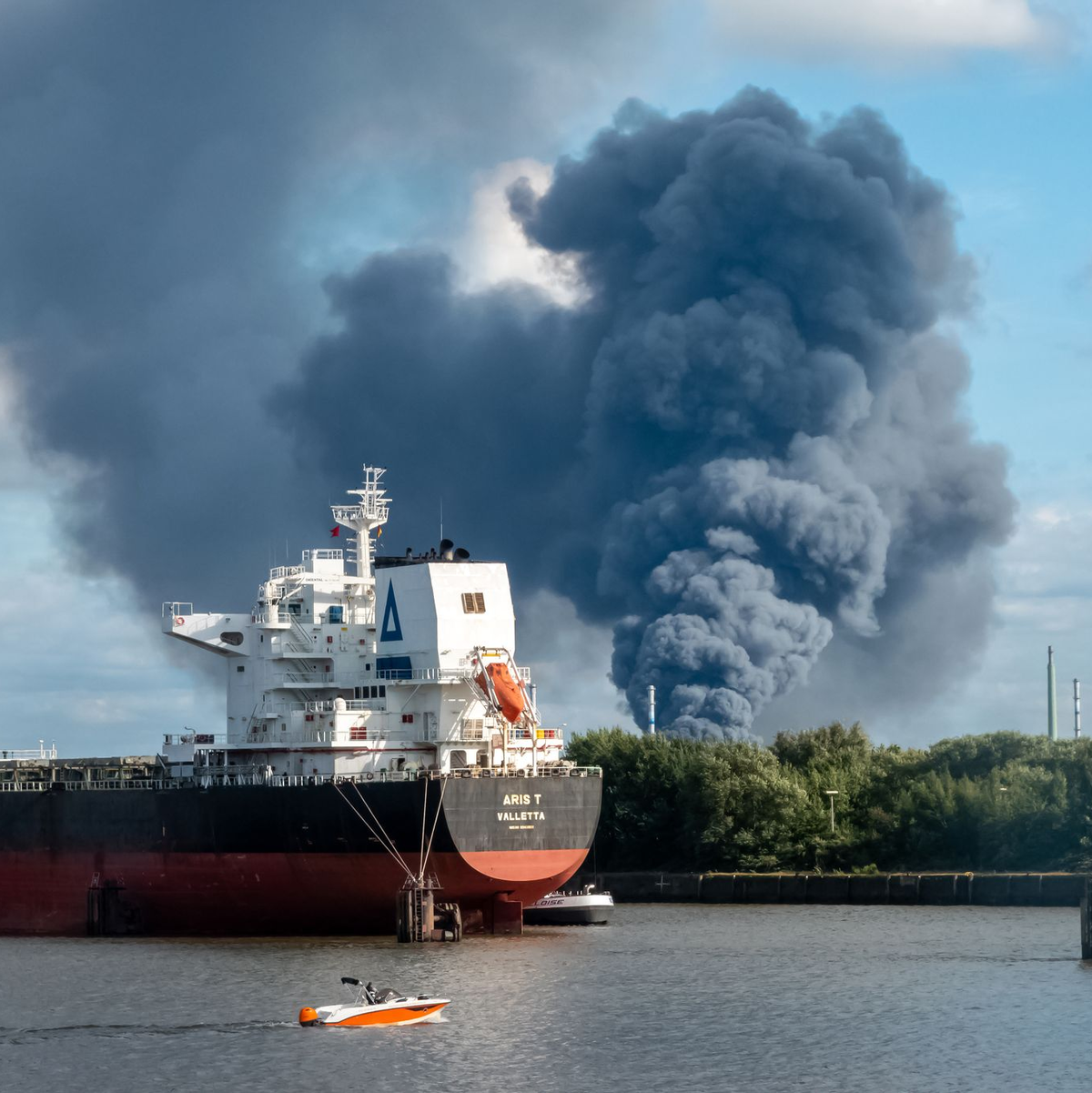 Rauch ist hinter einem Schiff zu sehen; in der Nähe des Einsatzortes fließt die Norderelbe.  - Foto: Bodo Marks/dpa