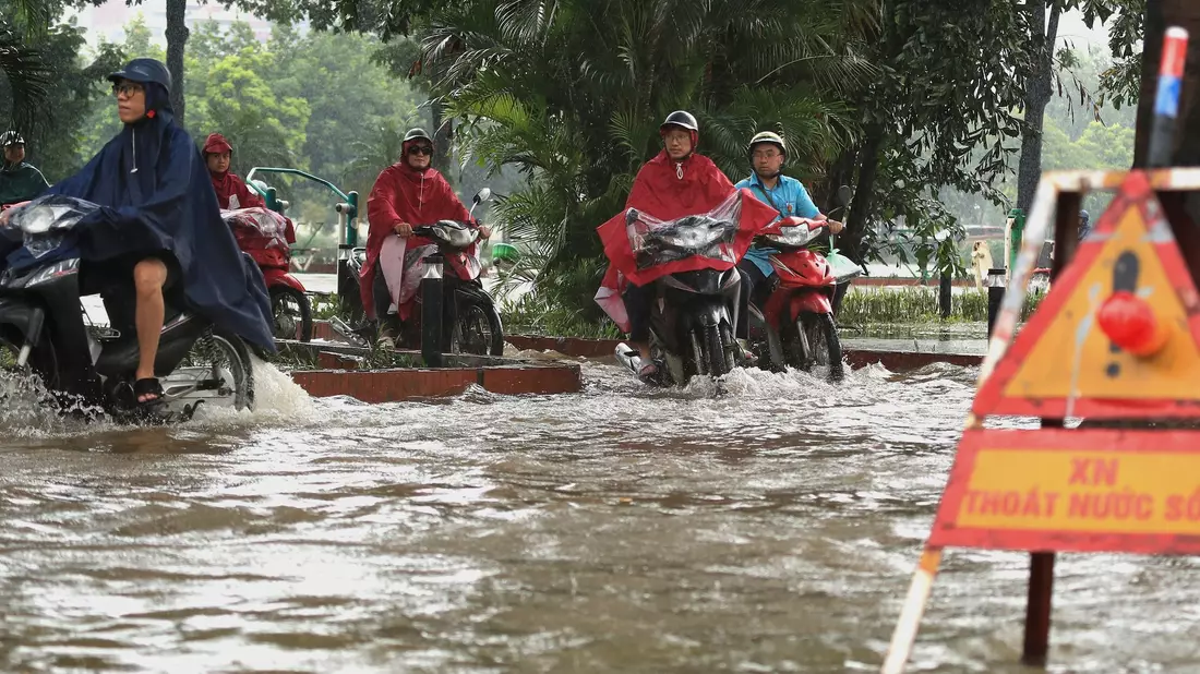 In Hanoi bahnten sich viele Motorradfahrer ihren Weg durch die Wassermassen. - Bild: Huy Han/AP/dpa