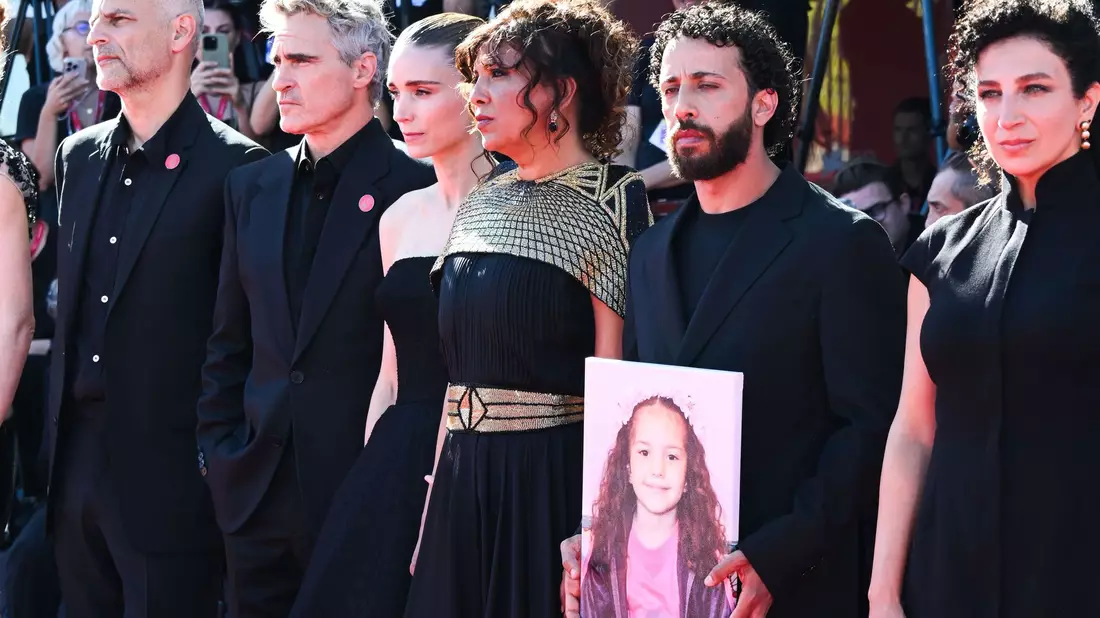 Joaquin Phoenix und Rooney Mara mit einem Teil des Filmteams und einem Foto von Hind Rajab auf dem roten Teppich.  - Bild: Mickael Chavet/ZUMA Press Wire/dpa