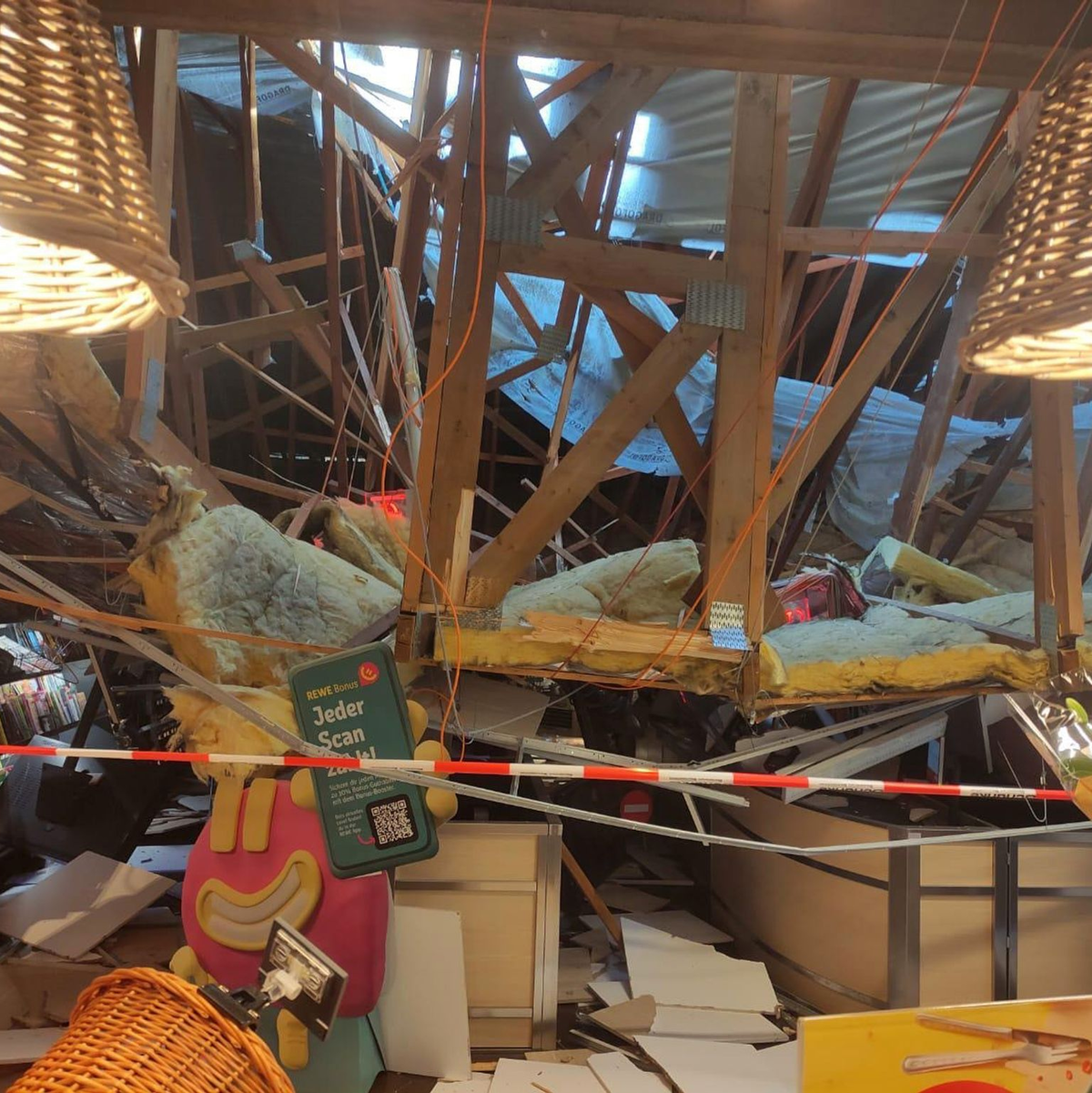 Vom Korb einer Drehleiter heraus kontrolliert ein Feuerwehrmann den eingestürzten Dachbereich. - Foto: Freiwillige Feuerwehr Lauchringen/dpa