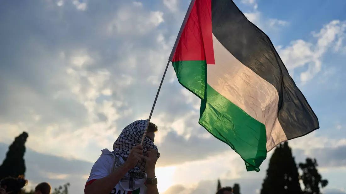 Ein Demonstrant schwenkt eine palästinensische Flagge während einer Demonstration vor dem griechischen Parlament. (Archivbild) - Bild: Petros Giannakouris/AP/dpa