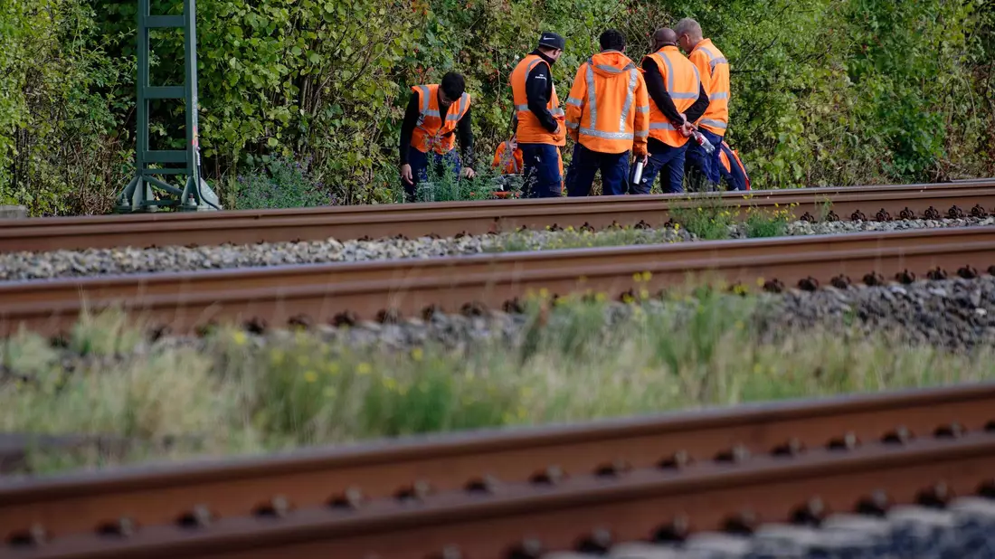 Bahn-Mitarbeiter stehen am Rand der Strecke Köln-Düsseldorf.  - Bild: Henning Kaiser/dpa