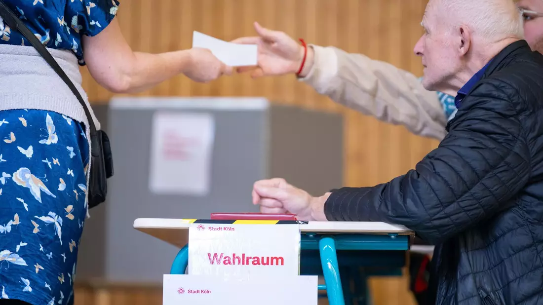 Eine Wahlhelferin gibt einen Stimmzettel aus. Landesweit fällt die Wahlbeteiligung unterschiedlich aus.  - Bild: Benjamin Westhoff/dpa