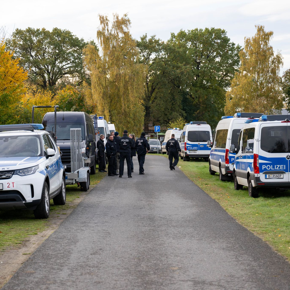 Polizisten stehen vor einem Grundstück in Tauche. - Foto: Christophe Gateau/dpa