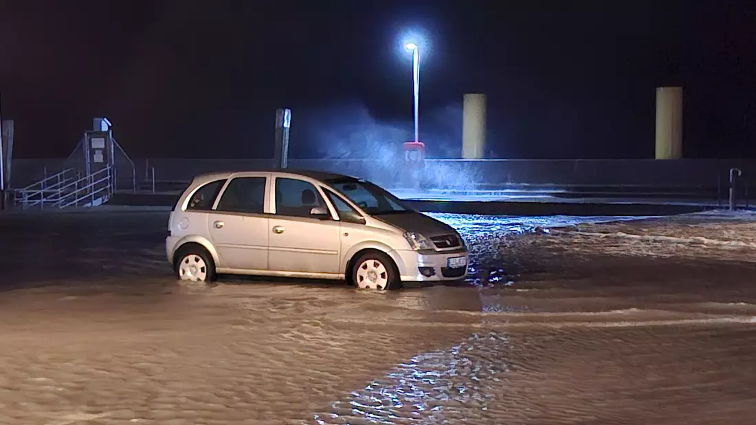 In Wilhelmshaven steht ein Auto auf einem überfluteten Parkplatz.  - Bild: Kai Moorschlatt/dpa