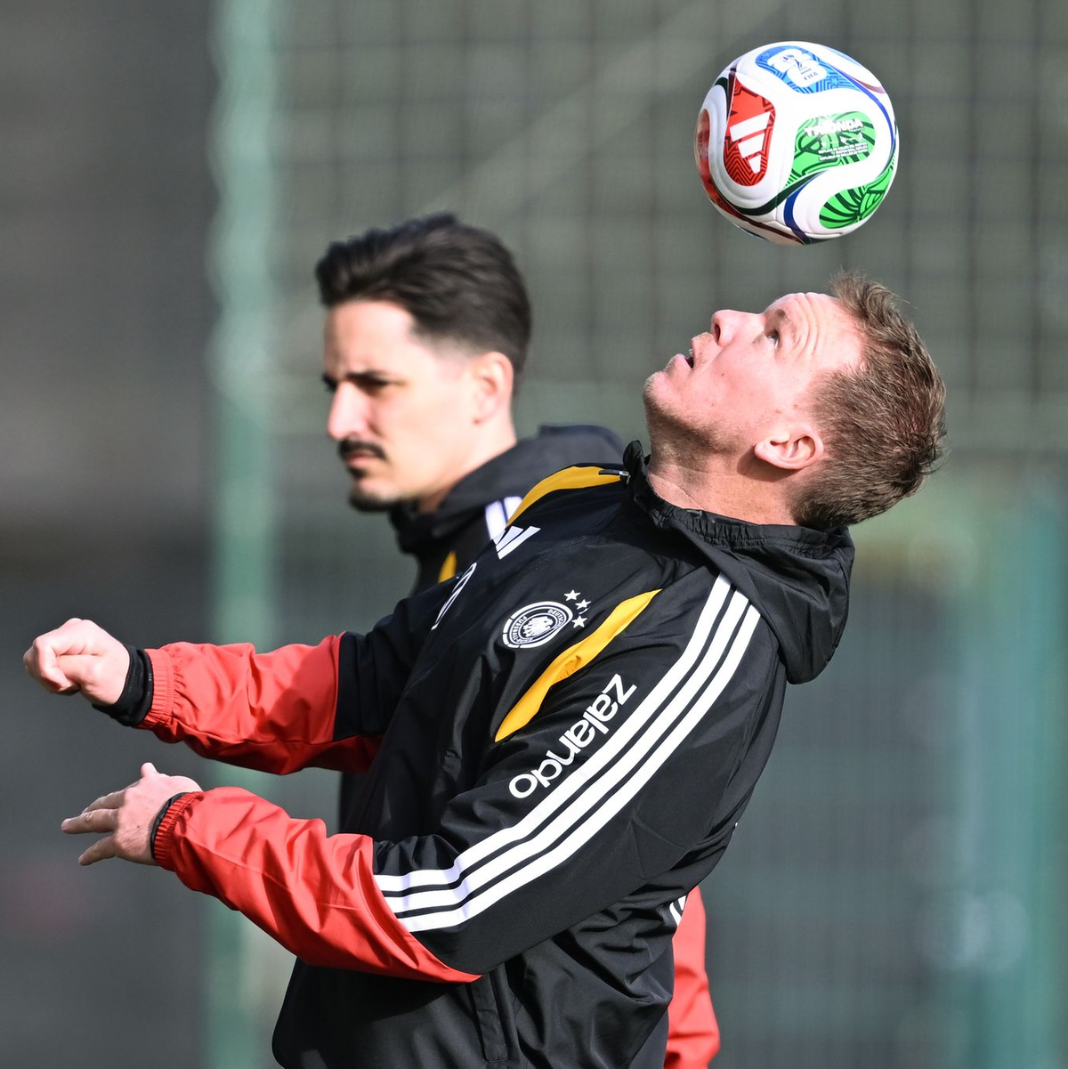 Mit Teamarzt Hahne (2.v.l.) betritt Schlotterbeck (l.) den Trainingsplatz.  - Foto: David Inderlied/dpa