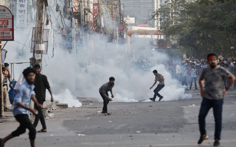 Demonstranten werfen Steine und rufen Parolen während einer Auseinandersetzung mit der Polizei in Bangladesch. - Foto: Rajib Dhar/AP/dpa