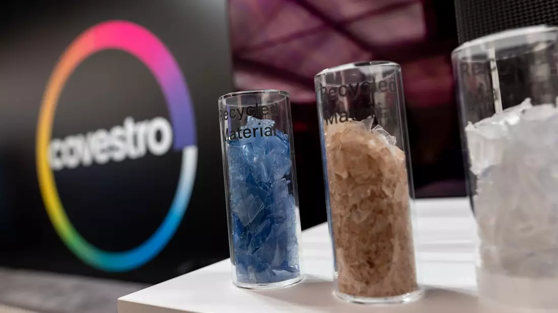 Eine deutsche Firma wird arabisch: Das Logo des Spezialchemie-Konzerns in einem Firmen-Showroom, davor Gläser mit Covestro-Materialien.  - Bild: Fabian Strauch/dpa