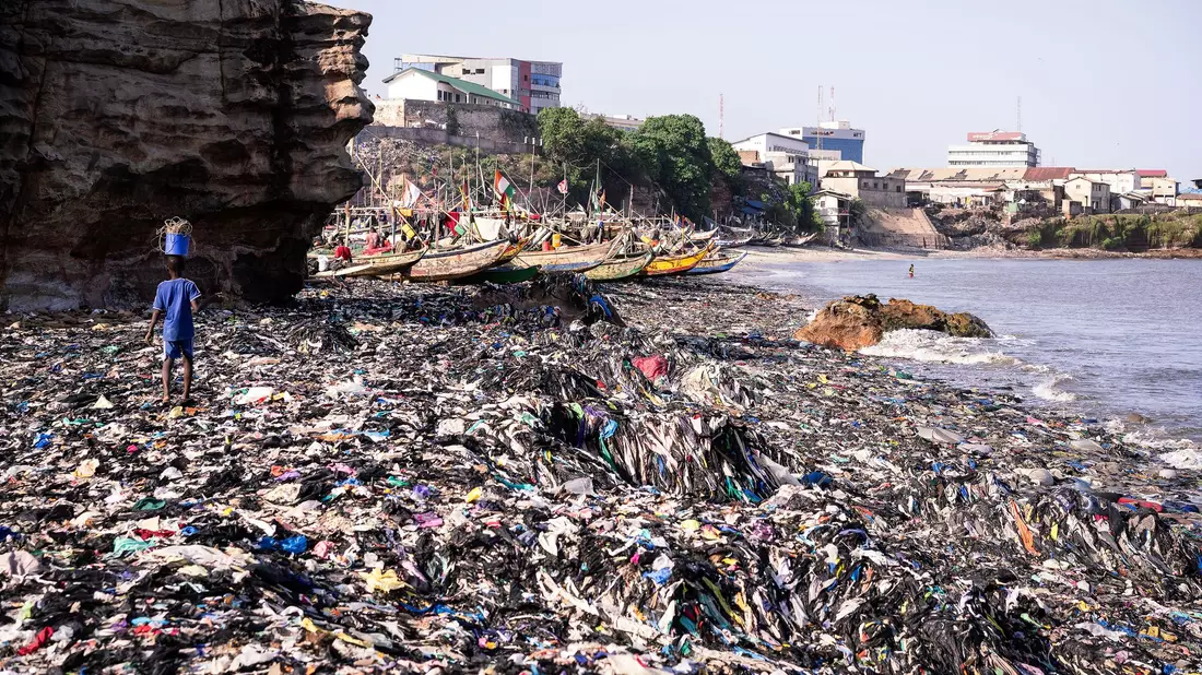 Ein Sandstrand, dessen Sand gar nicht mehr zu sehen ist: Massen an Klamotten vermüllen diesen Küstenabschnitt von Accra.  - Bild: Kevin McElvaney/Deutsche Umwelthilfe/dpa