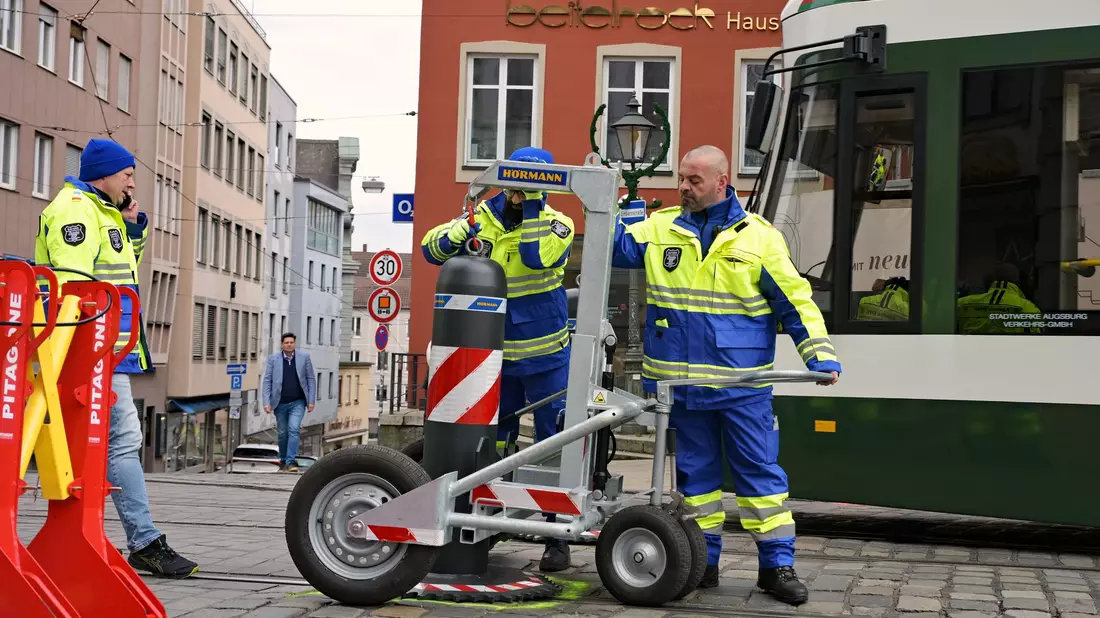 Zu den Hauptverkehrszeiten müssen Sicherheitsmitarbeiter neben dem Augsburger Christkindlesmarkt jede Stunde dutzendfach schwere Poller bewegen, damit die Straßenbahnen durchfahren können. - Bild: Malin Wunderlich/dpa