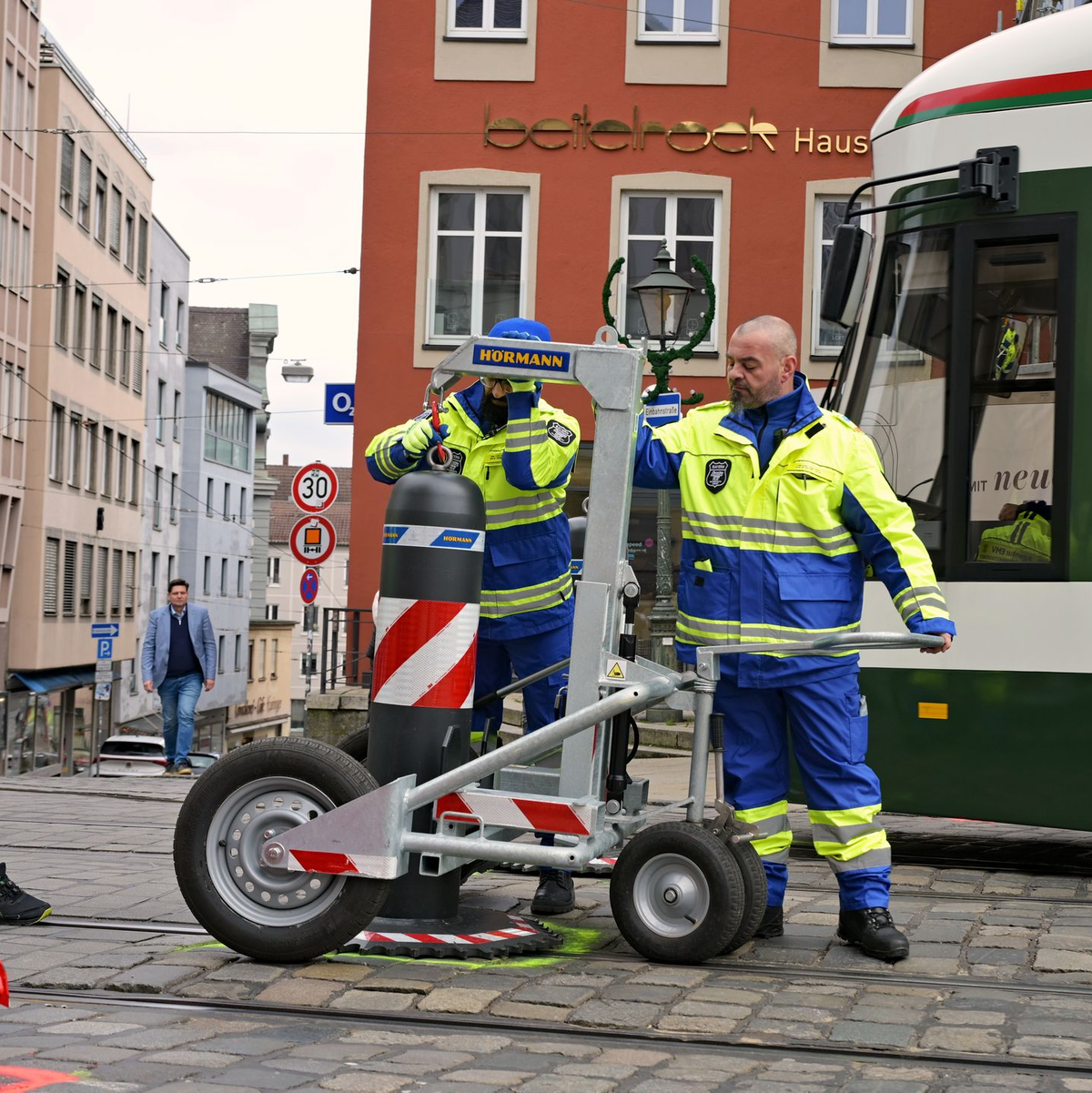 Zu den Hauptverkehrszeiten müssen Sicherheitsmitarbeiter neben dem Augsburger Christkindlesmarkt jede Stunde dutzendfach schwere Poller bewegen, damit die Straßenbahnen durchfahren können. - Foto: Malin Wunderlich/dpa