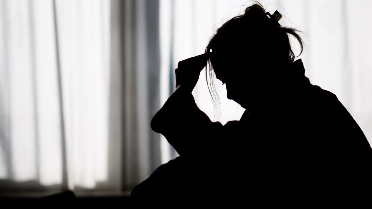 Silhouette einer Frau vor einer hellen Fensterfront - Foto: Julian Stratenschulte/dpa