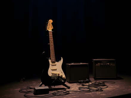 Kurz vor dem Soundcheck: Eine elektrische Gitarre wartet im Bühnenlicht neben den Amps auf ihren großen Einsatz. - Foto: THN