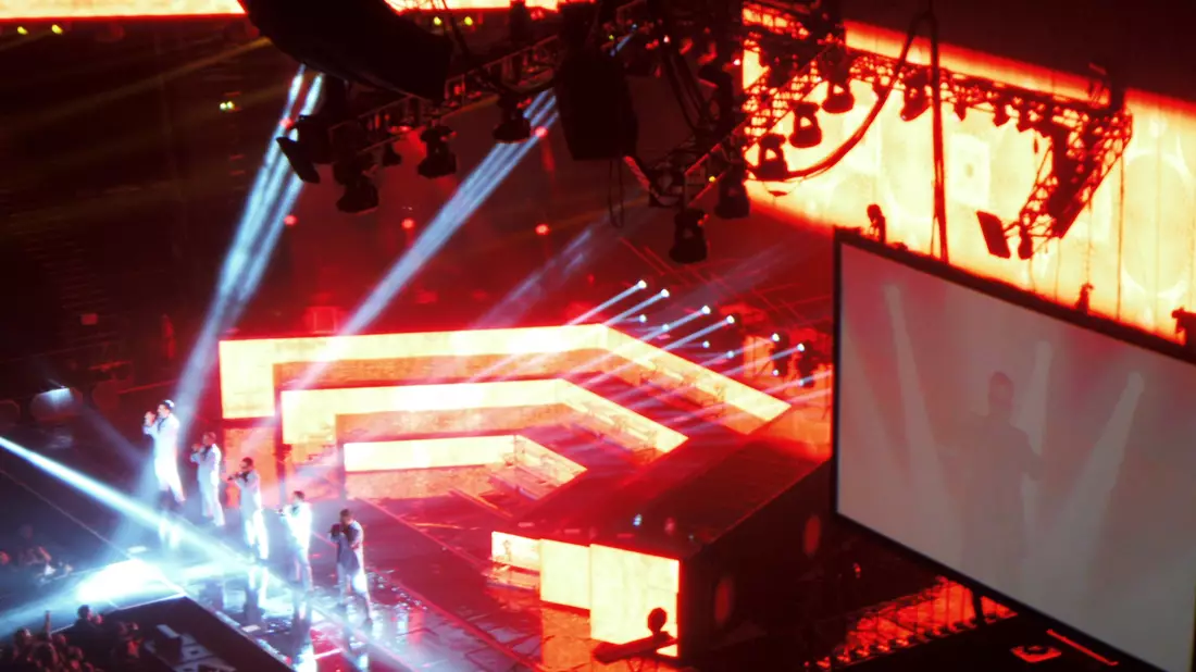 Konzertbühne in einer Arena von oben mit roter Lichtshow und Großbildleinwand