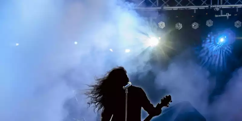 Energie pur auf der Bühne: Mit fliegender Mähne und Gitarre wirft sich der Musiker in den Nebel, umrahmt von kaltem Scheinwerferblau. - Foto: THN