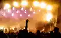 Symbol der Begeisterung: Eine Hand formt die Rockgeste vor einem Meer aus goldgelben und pinken Lichtern der Festivalbühne. - Foto: THN