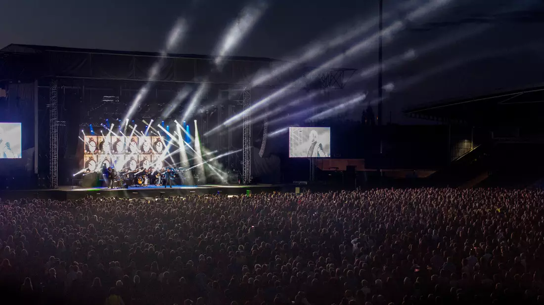 Großes Stadionkonzert mit Lichtshow, Videoleinwand und Menschenmenge bei Dunkel