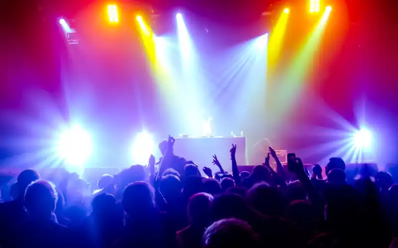 Farbenrausch auf dem Dancefloor: Hinter dem Pult treibt der DJ die Menge an, eingerahmt von einem Wirbel aus bunten Strahlen. - Foto: THN