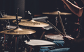 Puls der Musik: Die Drumsticks wirbeln über Snare und Becken, während warmes Licht die Nahaufnahme des Spiels einfängt. - Foto: THN