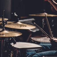 Puls der Musik: Die Drumsticks wirbeln über Snare und Becken, während warmes Licht die Nahaufnahme des Spiels einfängt. - Foto: THN