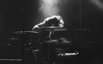 Hingabe in Schwarzweiß: Tief über das Drumset gebeugt verschwindet der Schlagzeuger fast im hellen Lichtkegel von oben. - Foto: THN