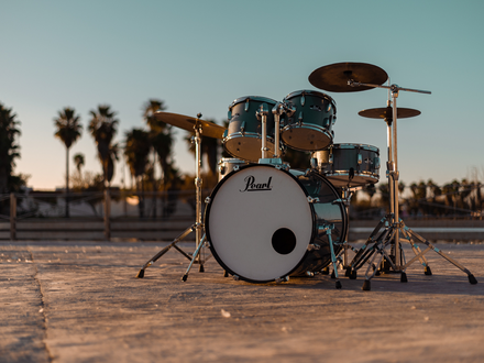 Ungewöhnliche Bühne: Ein türkisfarbenes Drumset steht einsam unter Palmen, während die Abendsonne die Szene in Gold taucht. - Foto: THN
