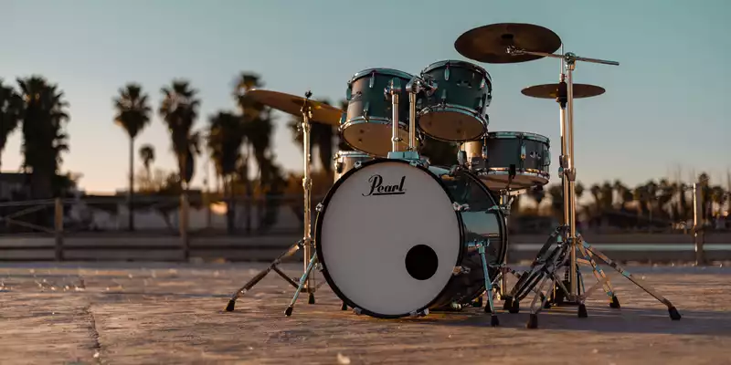 Ungewöhnliche Bühne: Ein türkisfarbenes Drumset steht einsam unter Palmen, während die Abendsonne die Szene in Gold taucht. - Foto: THN