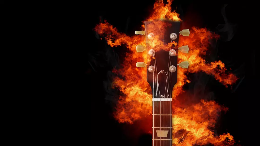 Brennender Gitarrenhals mit Kopfplatte und Flammen vor schwarzem Hintergrund