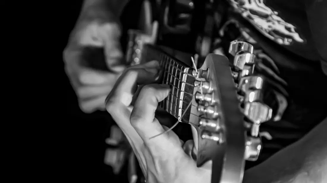 Hand greift Akkord am Gitarrenhals in Nahaufnahme als Schwarzweißaufnahme