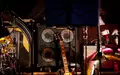 Bereit für laute Töne: Eine rote E-Gitarre lehnt an einer mächtigen Box mit vier Lautsprechern inmitten des Bühnenequipments. - Foto: THN